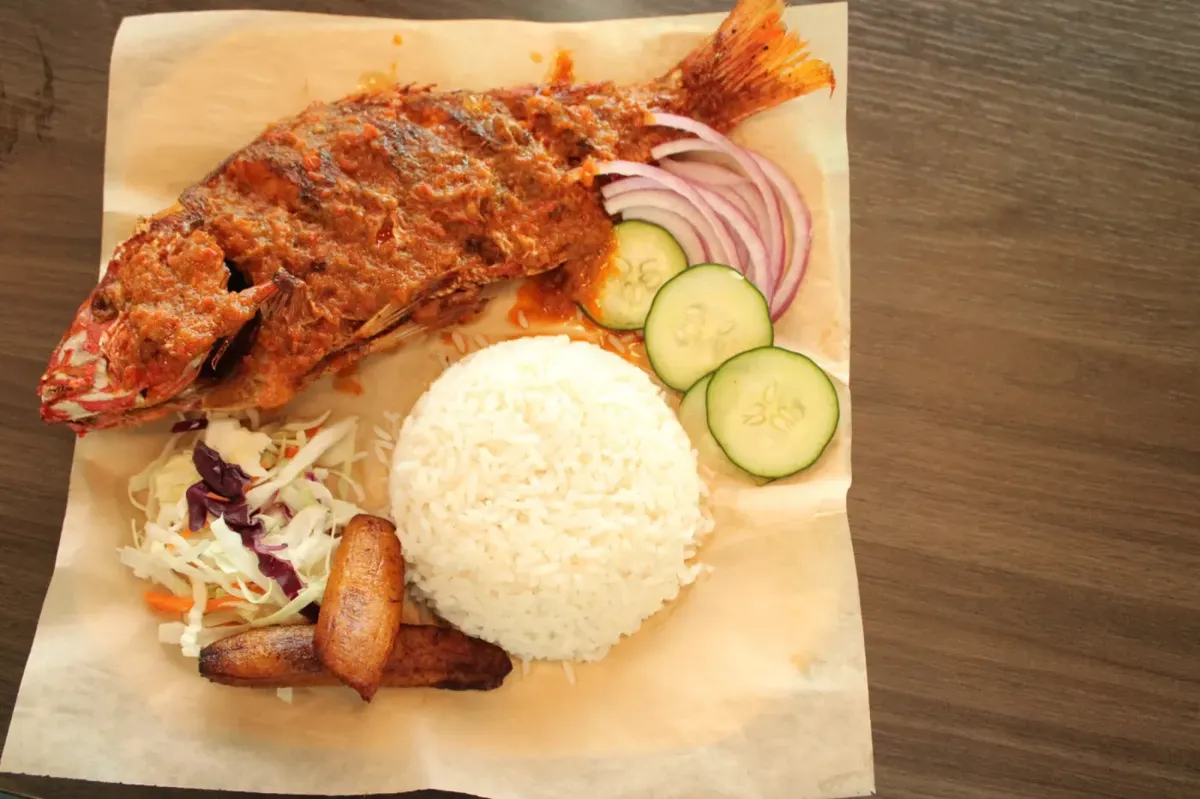 Whole fish served with white rice, cucumber, onion, and plantain